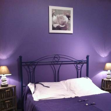 Lit dans une chambre peinte en violet en Charente Maritime